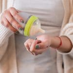 Photo of mom testing temperature of baby bottle